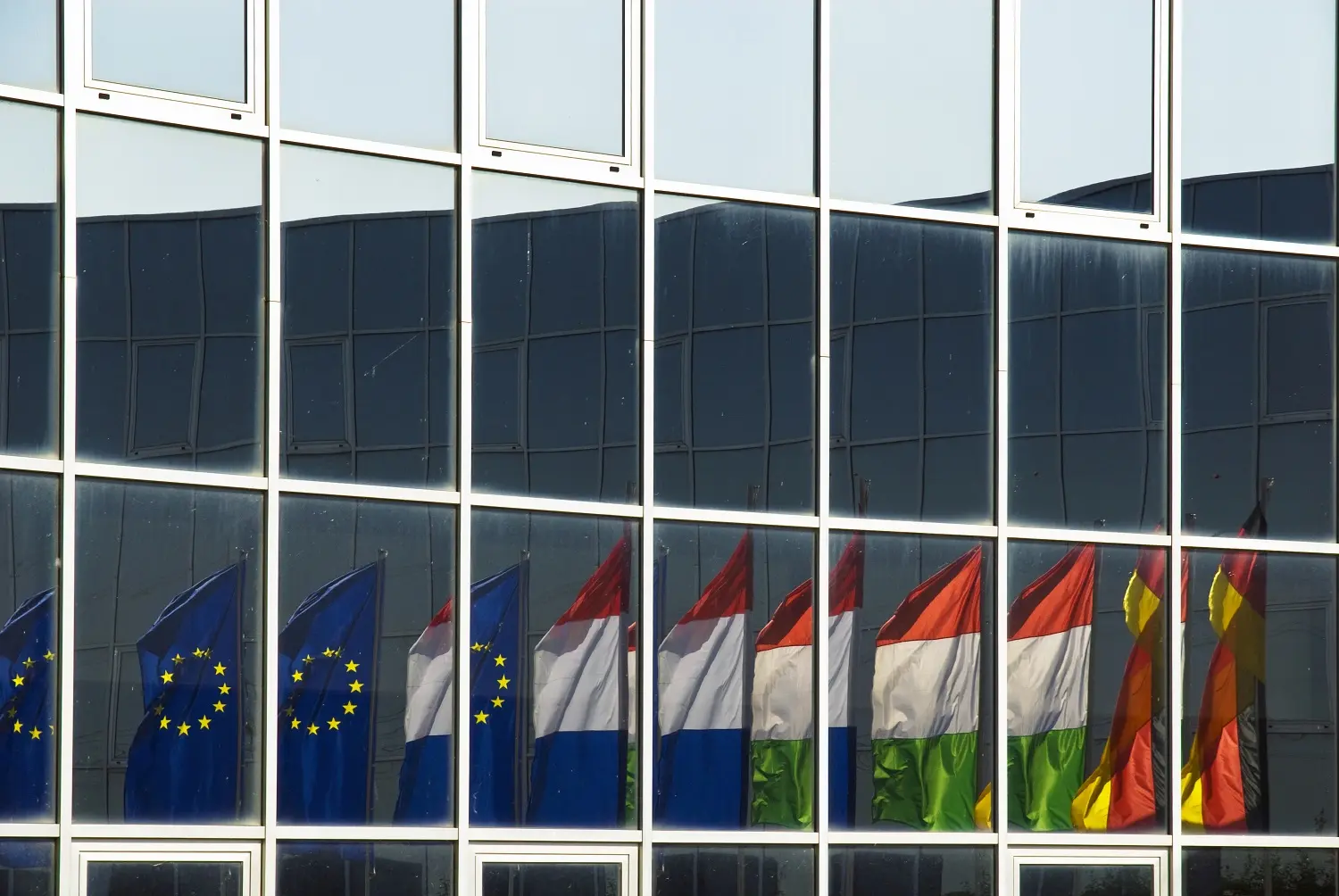 Regierungsgebäude mit HaverkampShielding silber dunkel 16R RS sr Primus Plus, in dem sich Europaflaggen spiegeln.