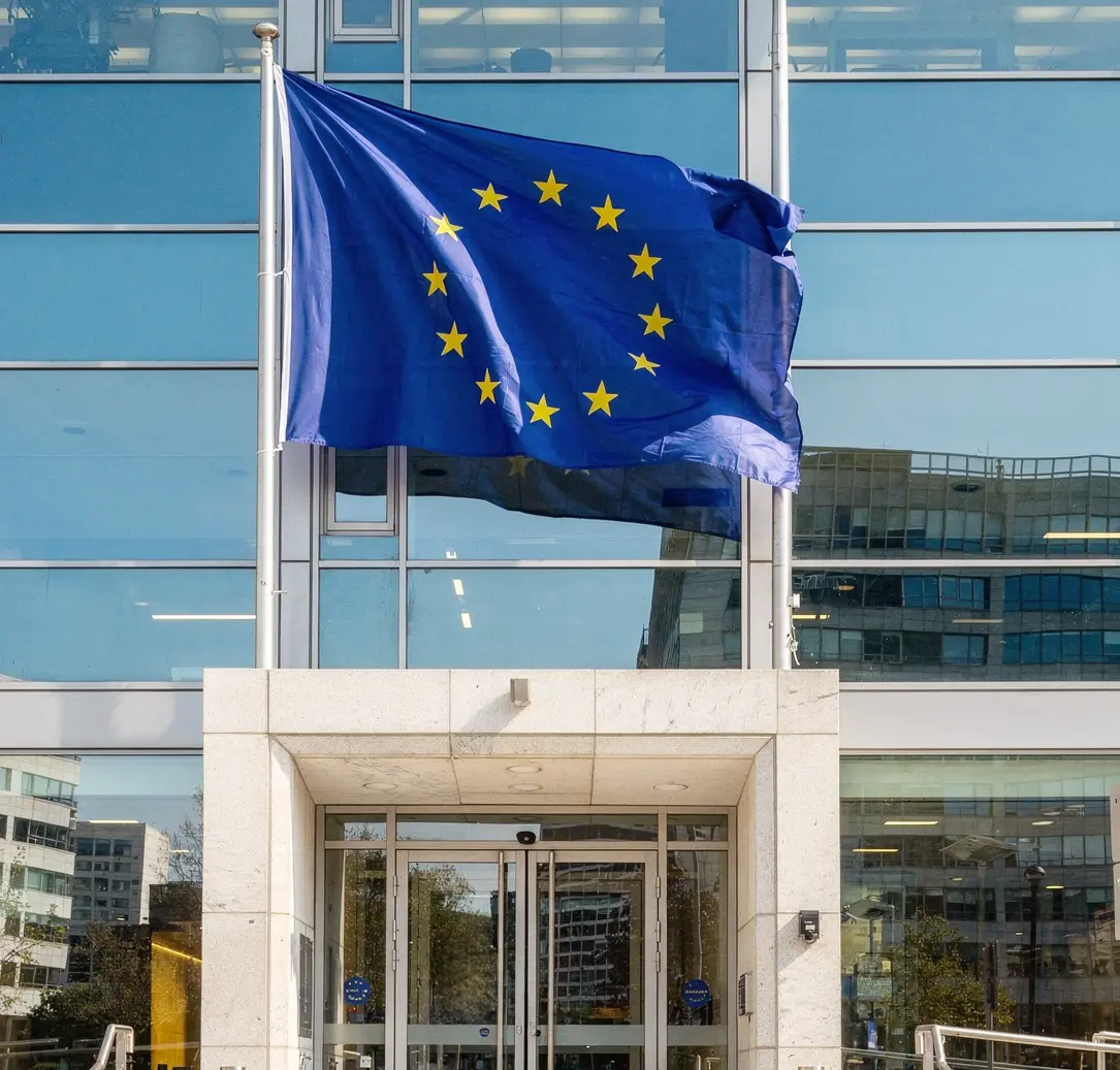 EU-Flagge vor Gebäude mit Haverkamp Shielding dunkel 16 RS sr silber Abhörschutzfolie auf der Glasfassade.