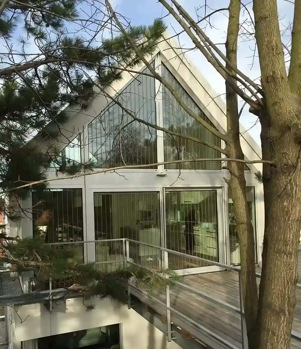 Modernes Wohnhaus mit Haverkamp birdsafe® Vogelschutzfolie mit Rautenmuster orange schwarz, umgeben von Bäumen.